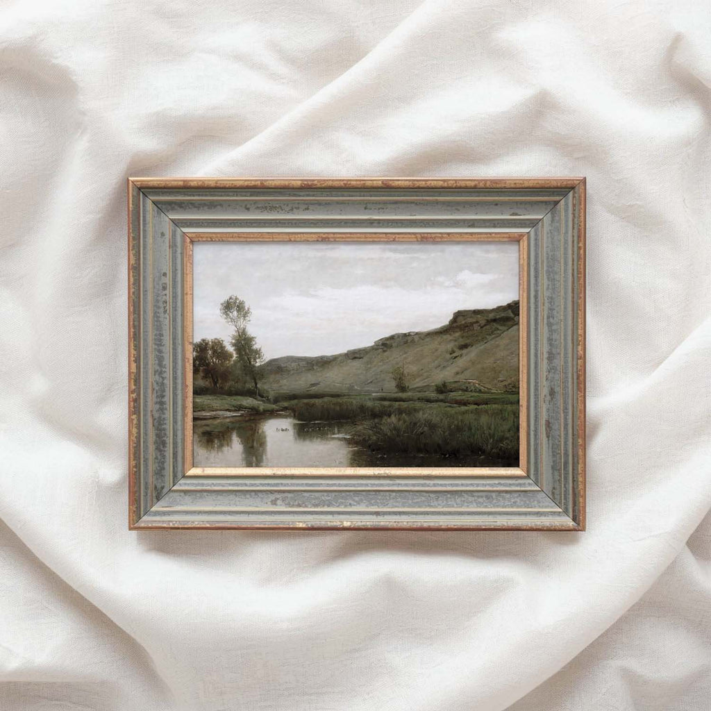 Muted green landscape wall art depicting a peaceful river beneath a rocky hillside